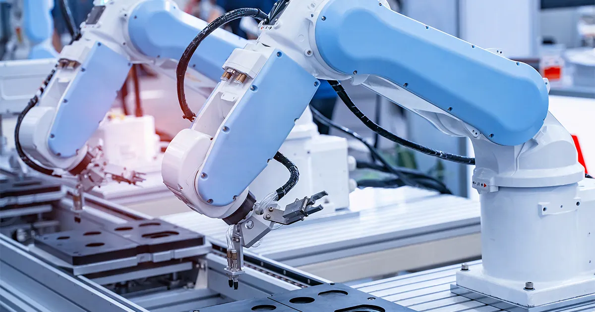 Automated robotic arms with blue and white casings in a high-tech manufacturing environment, suggesting advanced production and digital transformation.