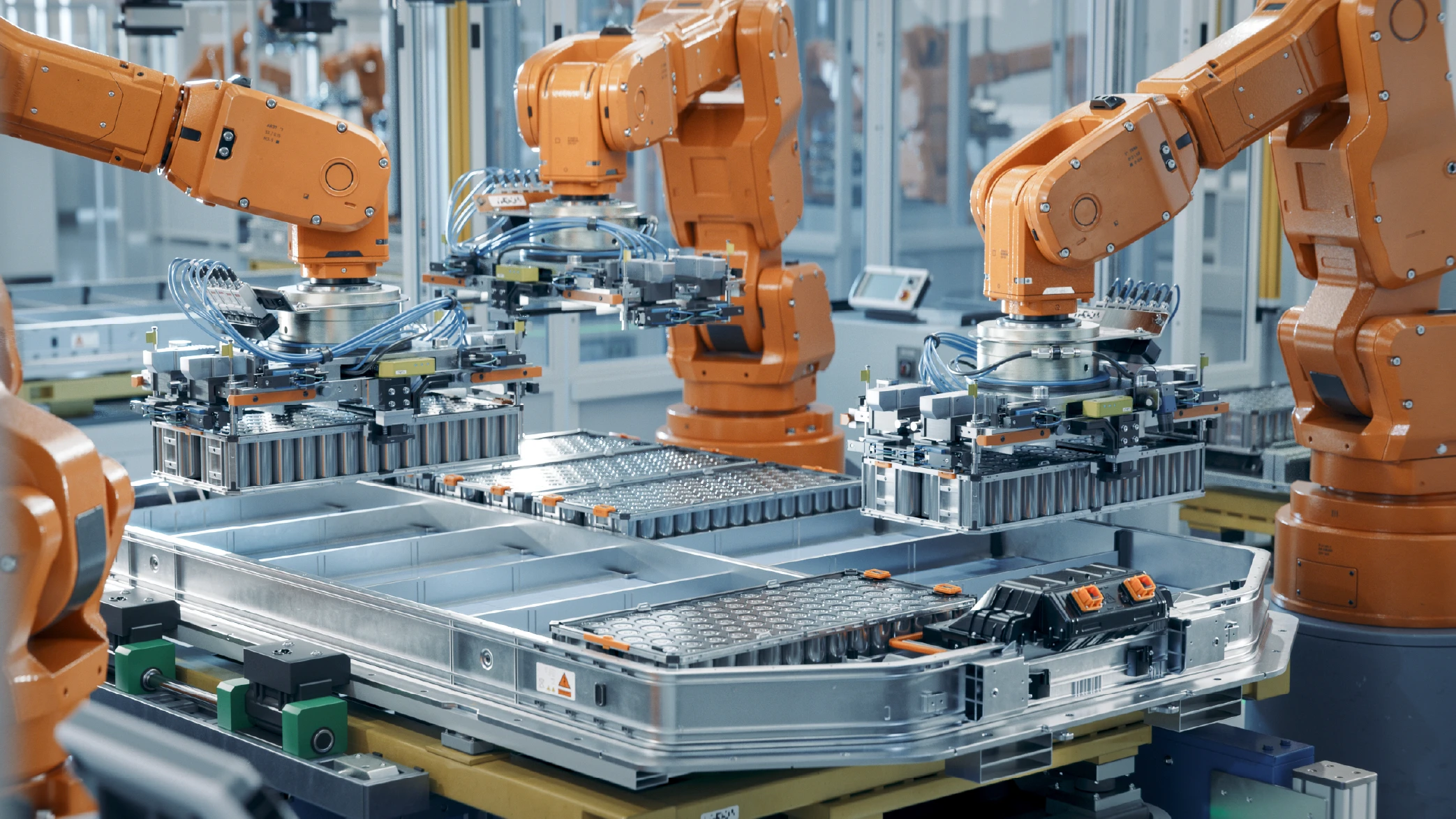 Orange robotic arms precisely assembling electric vehicle battery packs on an automated manufacturing line, crucial for advanced production planning and MES solutions in the automotive industry.